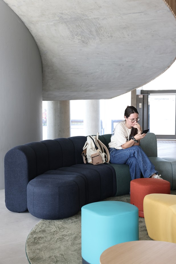 Étudiante assise dans le hall du campus de l’ESMA, espace de détente moderne.