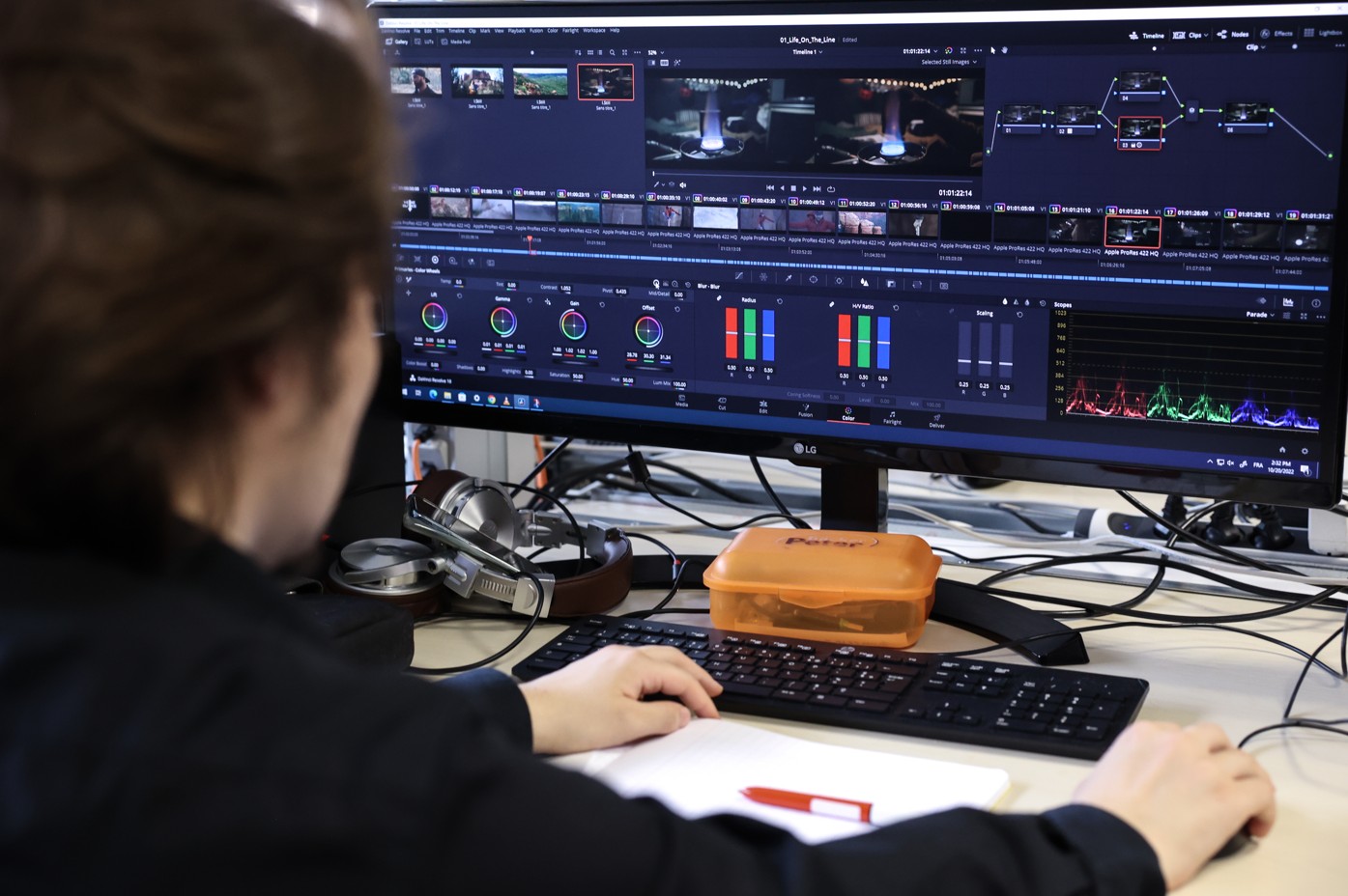 Un étudiant travaille sur un logiciel de montage et d’étalonnage vidéo, affiché sur un grand écran avec courbes colorimétriques et timeline.