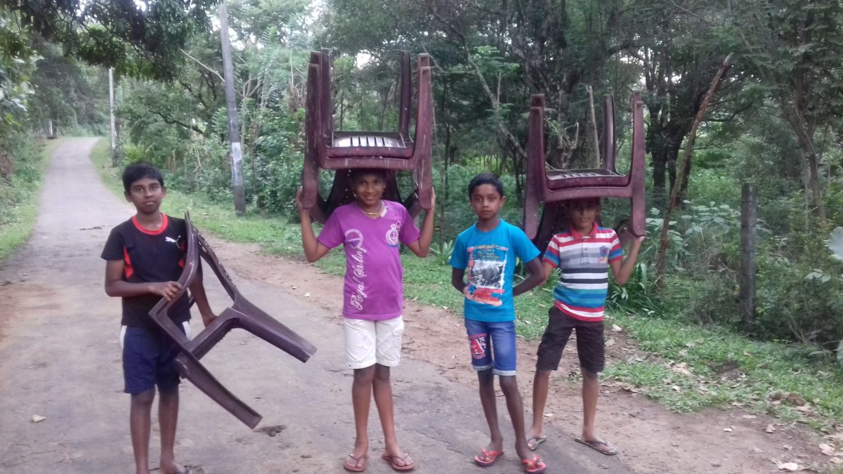 Enfants sri lankais portant des chaises en plastique